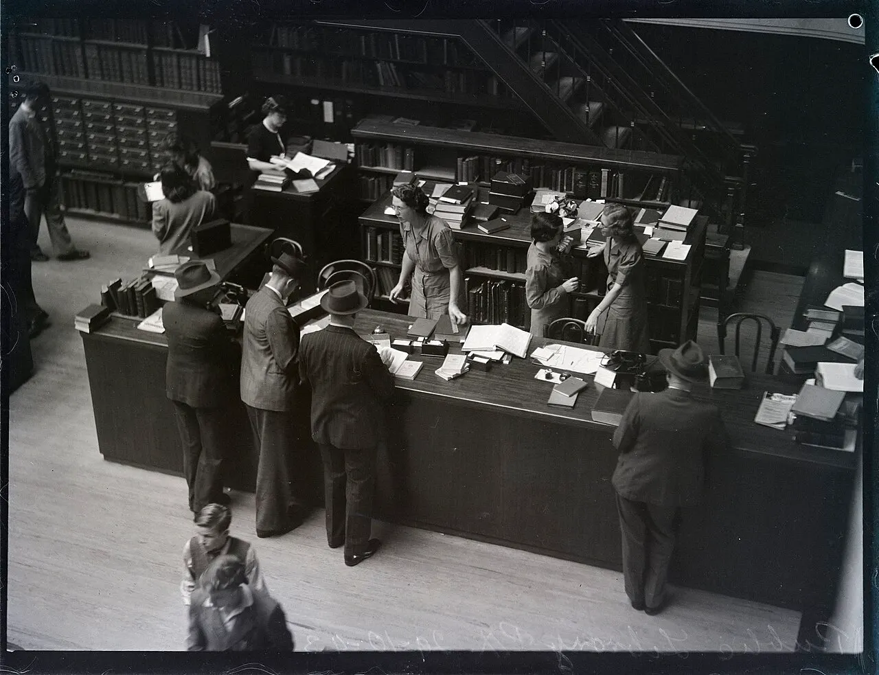 reference desk in the State Library of New South Wales reading room, photographed in 1943; contextual archival image, not related to the McWhirters. Pix Magazine photographer; State Library of New South Wales, Wikimedia Commons, https://commons.wikimedia.org/wiki/File:Library_desk,_Reading_Room,_Mitchell_Building.jpg, CC BY-SA 3.0 AU (https://creativecommons.org/licenses/by-sa/3.0/au/deed.en). Attribution: State Library of New South Wales, “Library desk, Reading Room, Mitchell Building,” CC BY-SA 3.0 AU, via Wikimedia Commons. Resized to 1280 pixels wide; checked 2026-10-18.
