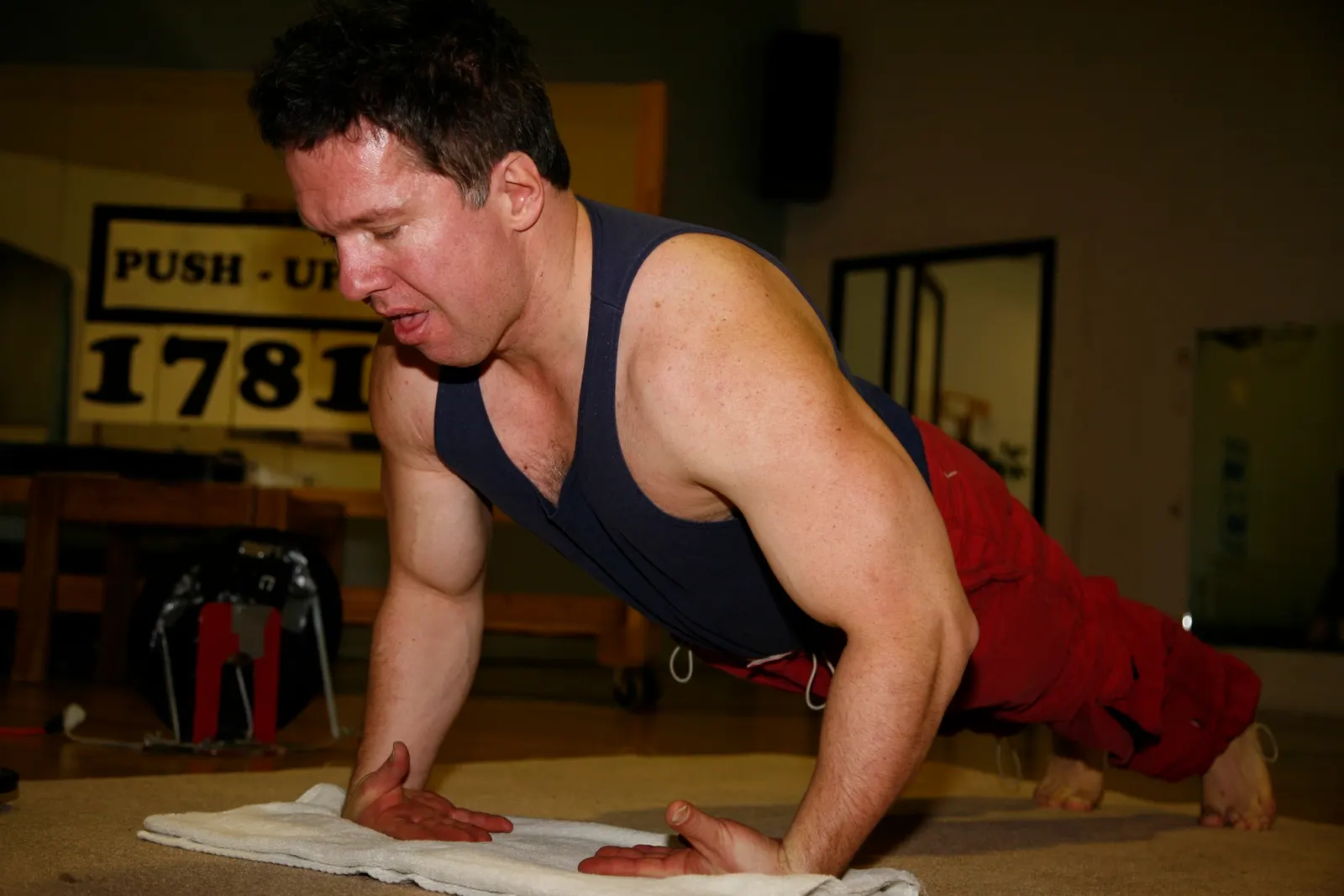 Canadian athlete Doug Pruden doing back-of-hands push-ups in an Edmonton gym during a 2005 record attempt; photographer Goudieman; CC0 1.0. Original page: https://commons.wikimedia.org/wiki/File:Doug_Pruden_doing_back_of_the_hand_push_ups_MG_0045.JPG. No attribution is legally required under CC0; attribution retained here: Goudieman, via Wikimedia Commons. License: https://creativecommons.org/publicdomain/zero/1.0/. Resized to 1800 px maximum dimension and saved as JPEG quality 88; no crop.
