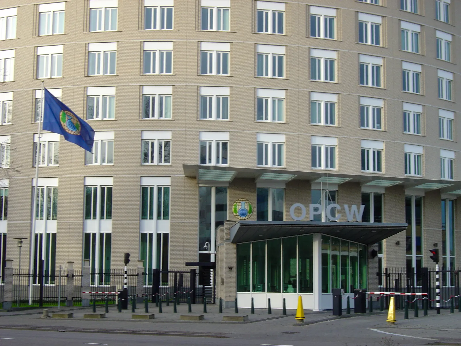 documentary photograph of the Organisation for the Prohibition of Chemical Weapons headquarters in The Hague. Creator: Szilas. [Wikimedia Commons file page](https://commons.wikimedia.org/wiki/File:Entrance_of_the_OPCW_HQ_in_The_Hague.jpg). CC BY-SA 4.0; attribution and share-alike terms apply; [license](https://creativecommons.org/licenses/by-sa/4.0/). No edits.