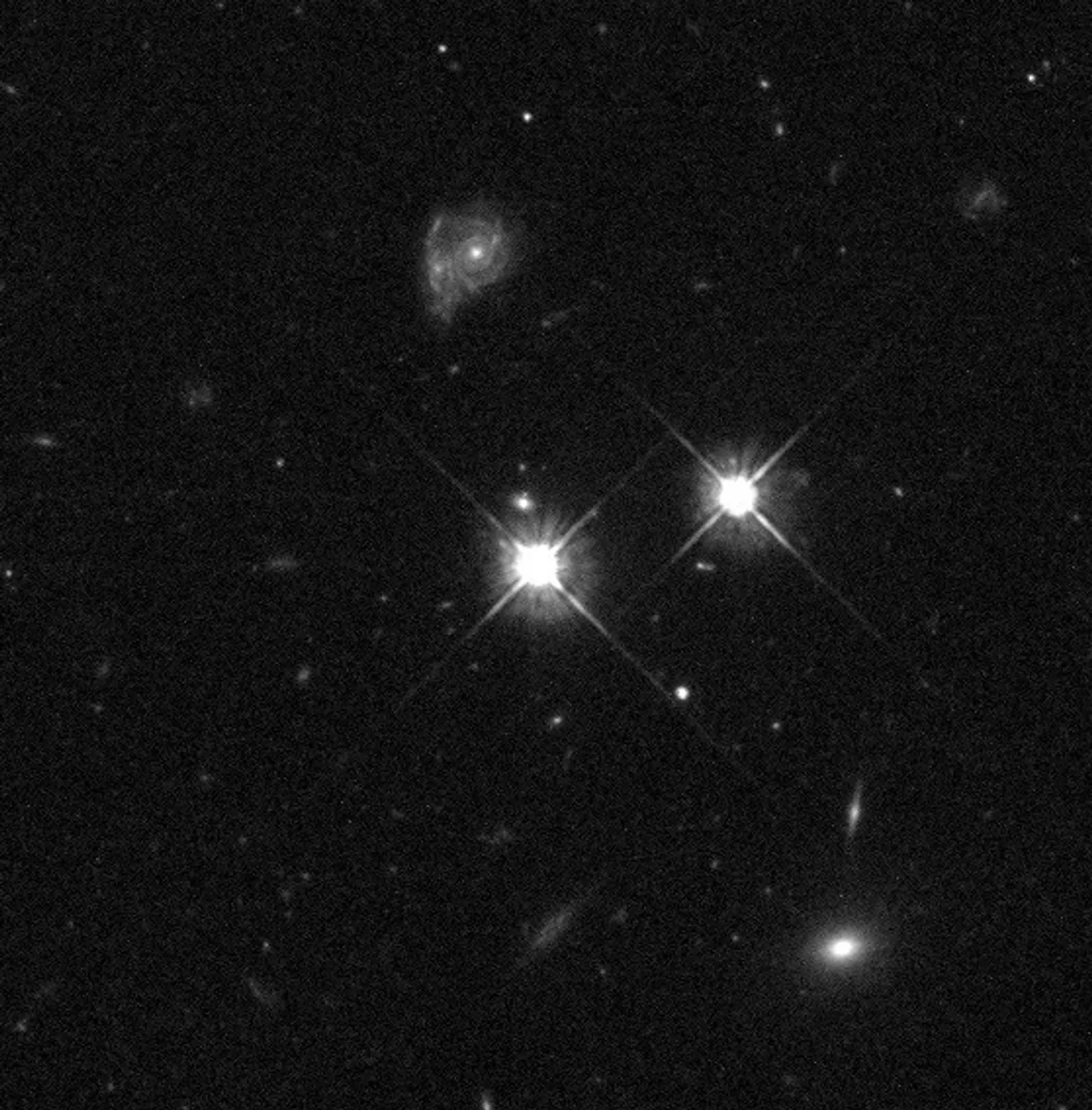 чорно-білий кадр Hubble із яскравим далеким квазаром та об'єктами на передньому плані.