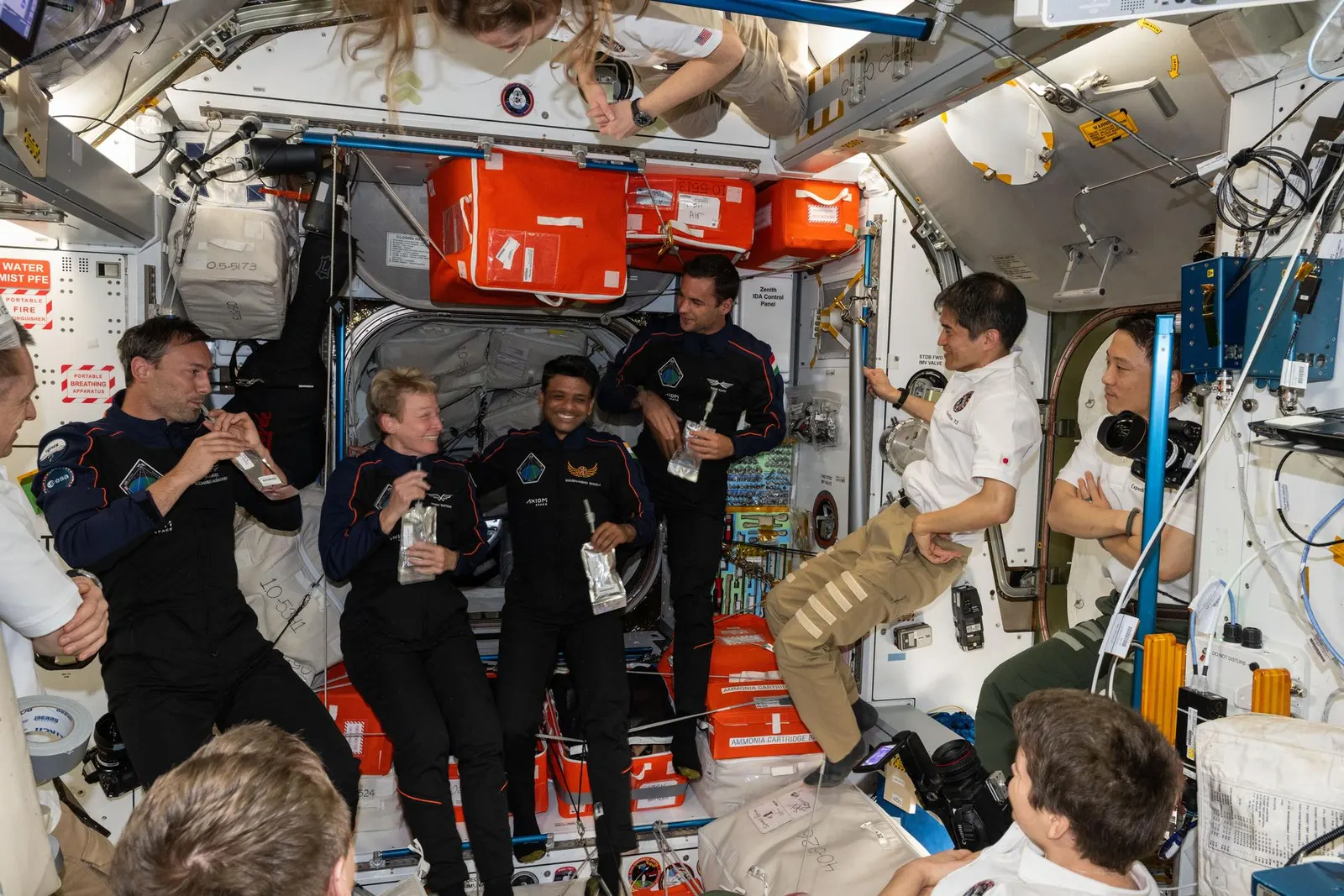 Axiom Mission 4 private astronauts inside the International Space Station, June 26, 2025. NASA/JSC photo ID iss073e0249239. Original page: https://commons.wikimedia.org/wiki/File:The_Axiom_Mission_4_private_astronauts_gather_inside_the_International_Space_Station_(iss073e0249239).jpg. NASA image, public domain as U.S. government work; attribution: “NASA/JSC.” 1920px NASA rendition, no crop.