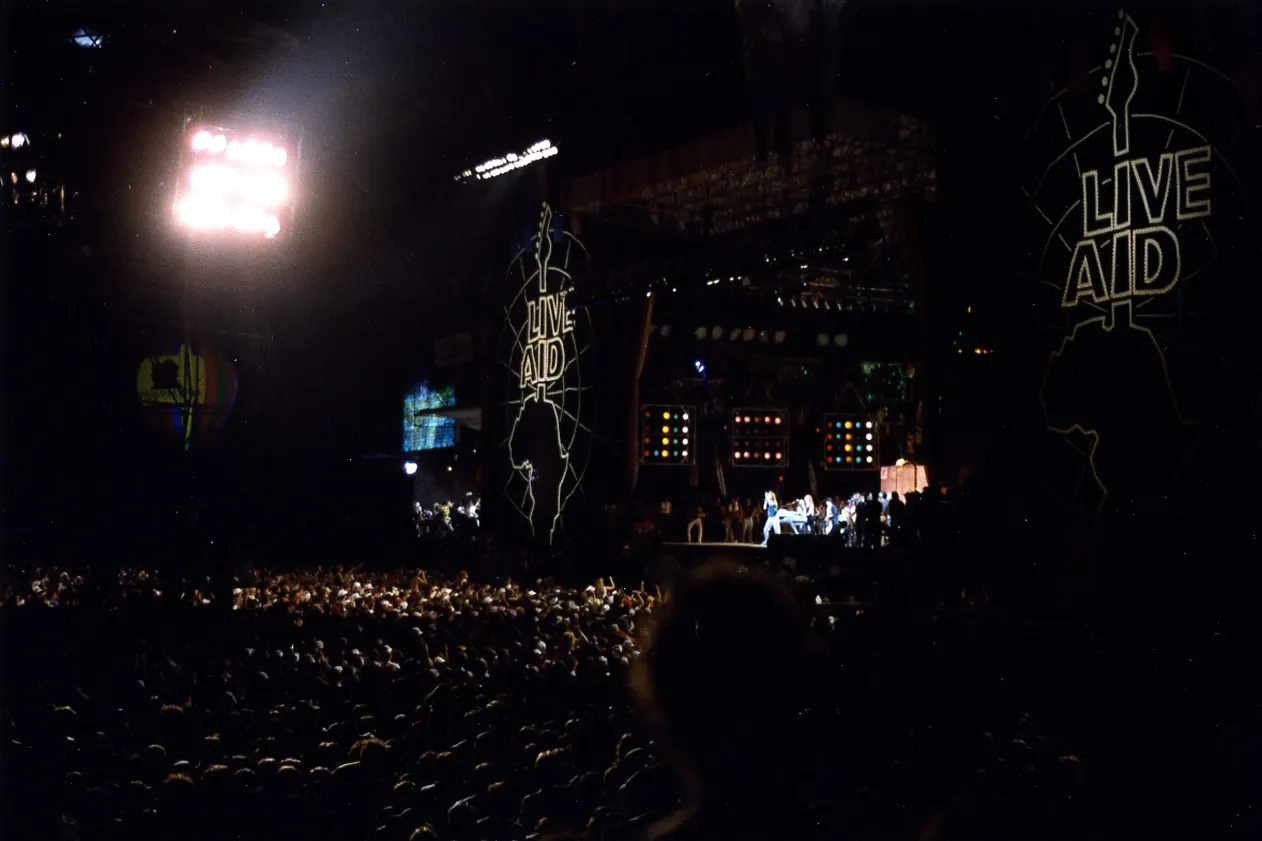 Squelle, photograph of Live Aid at JFK Stadium after dark on 13 July 1985; Wikimedia Commons CC BY-SA 3.0 (or GFDL); no edits. https://commons.wikimedia.org/wiki/File:Live_Aid_after_dark_at_JFK_Stadium,_Philadelphia,_PA.jpg