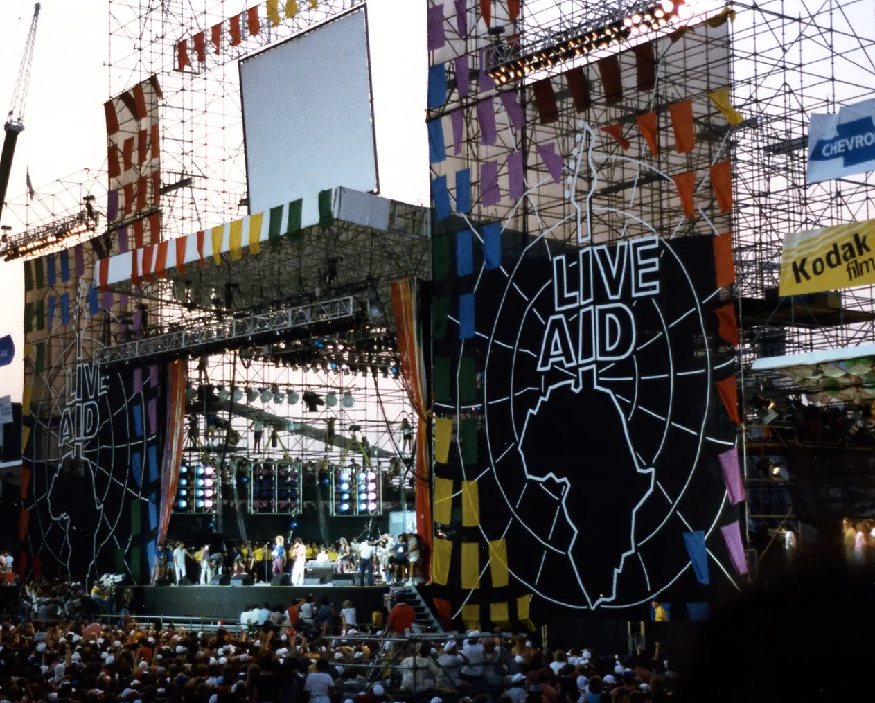 Squelle, photograph of Live Aid at JFK Stadium in Philadelphia on 13 July 1985; Wikimedia Commons CC BY-SA 3.0 (or GFDL); no edits. https://commons.wikimedia.org/wiki/File:Live_Aid_at_JFK_Stadium,_Philadelphia,_PA.jpg