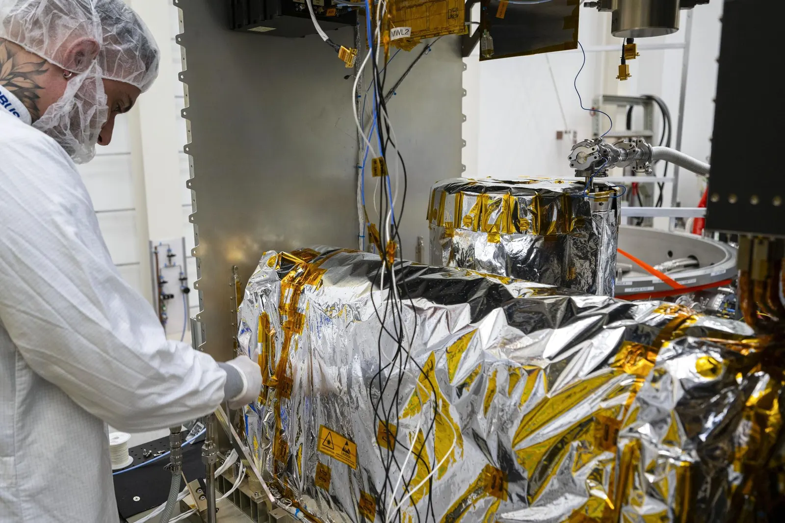 NASA image JSC2025E015677, technicians preparing ACES atomic-clock equipment on the ground, 2025. NASA credit; U.S. federal public-domain work. Source: https://images-assets.nasa.gov/image/jsc2025e015677/jsc2025e015677~large.jpg. It shows ground preparation, not the equipment in orbit or a measured human age difference.
