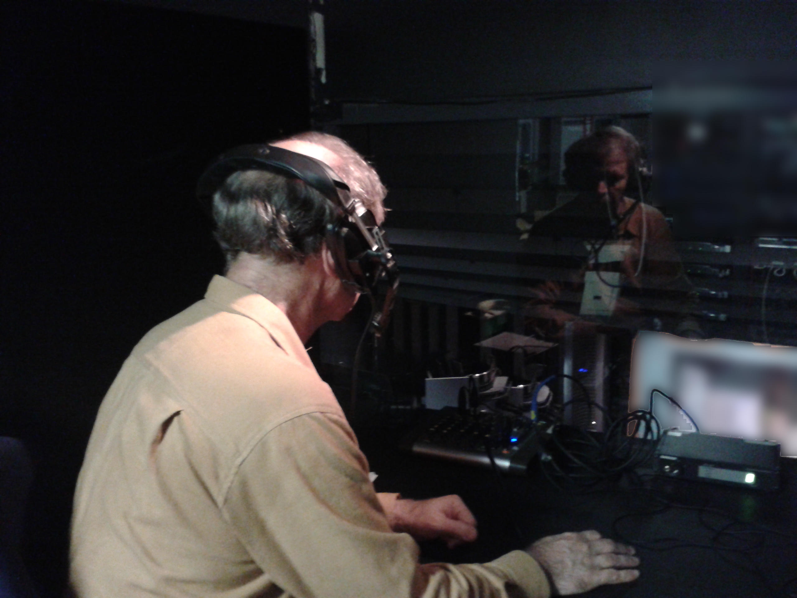 an audio describer working at a live-theater sound desk; creator MOAI12; public domain dedication by the creator; attribution optional, retained here as credit. Original: https://commons.wikimedia.org/wiki/File:Audio_describer_in_live_theater.jpg