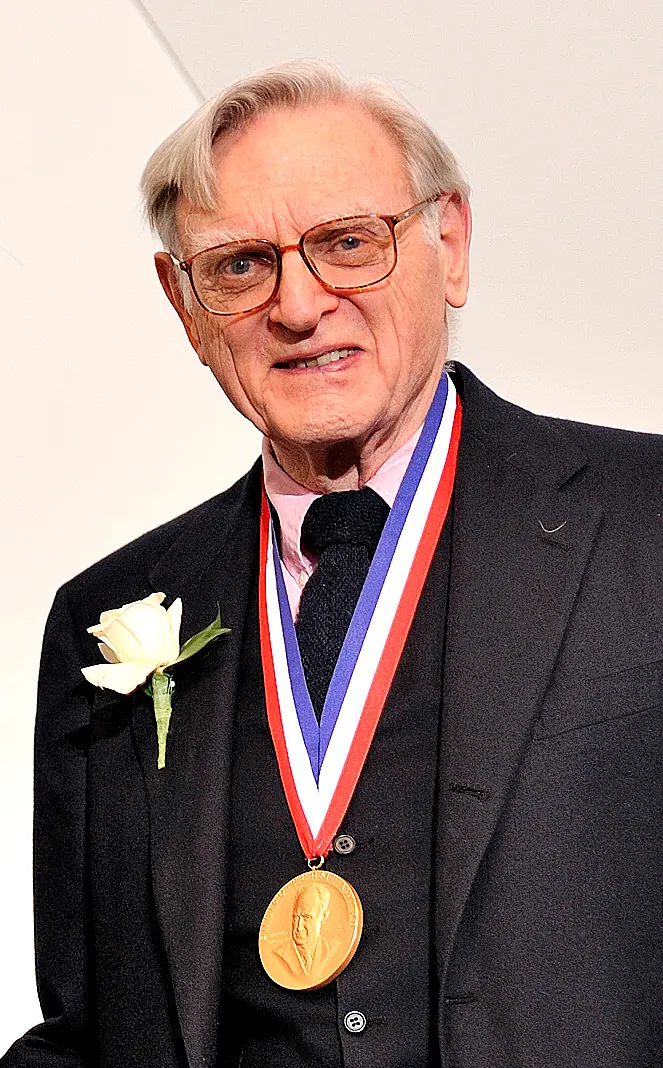 documentary photo of John B. Goodenough receiving the 2009 Enrico Fermi Award, taken in 2010. Original asset page: [Wikimedia Commons](https://commons.wikimedia.org/wiki/File:John_B._Goodenough_(2010)_(cropped).jpg); original source: [U.S. Department of Energy Flickr](https://www.flickr.com/photos/departmentofenergy/4272889986/). Creator/rights holder: U.S. Department of Energy. The file page identifies it as a work by a U.S. federal employee made in official duties and thus public domain in the United States; attribution: “U.S. Department of Energy, public domain, via Wikimedia Commons.” No crop or content edits. This depicts a different award, not the Nobel Prize or 2019 ceremony. Downloaded and visually checked 18 October 2026; 663×1068 px.