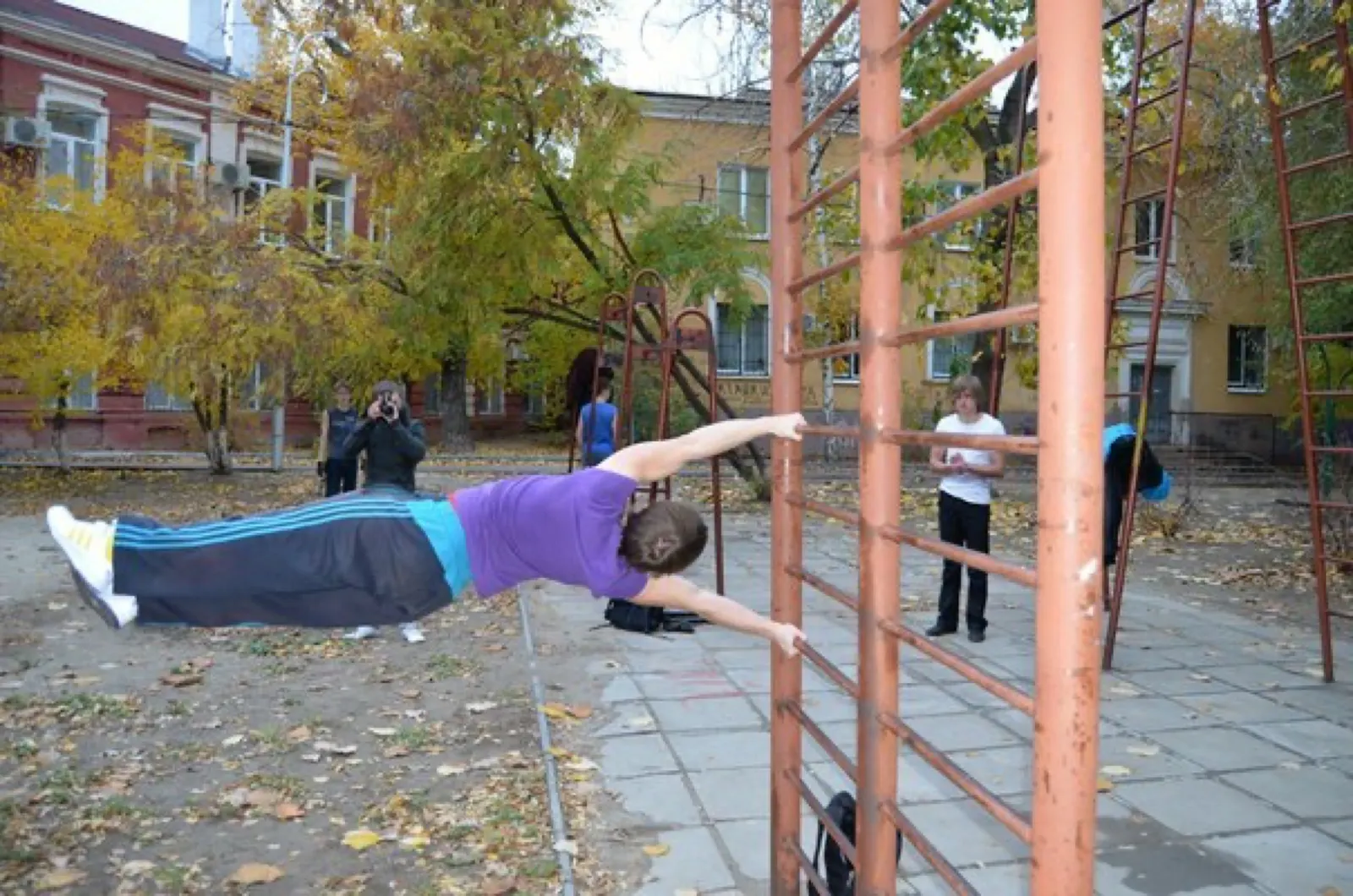a different athlete holding a human flag on playground bars; creator Extrem7; CC BY-SA 3.0. Original file page: https://commons.wikimedia.org/wiki/File:5_human_flag.jpg. Attribution: Extrem7, CC BY-SA 3.0, via Wikimedia Commons. License: https://creativecommons.org/licenses/by-sa/3.0/. Saved at 604 × 400 px as JPEG quality 88; no crop.