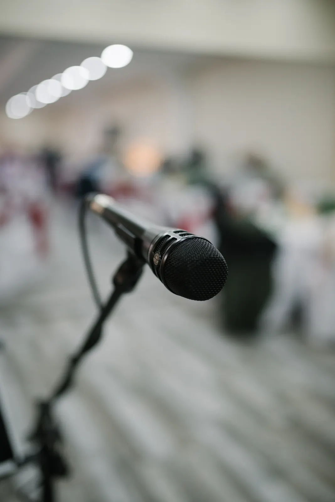 Microphone ready for a performance; Shixart1985, CC BY 2.0. Wikimedia Commons page: https://commons.wikimedia.org/wiki/File:A_microphone_stands_ready_on_a_stand,_awaiting_use_during_an_evening_event.jpg. Attribution to Shixart1985; no edits.