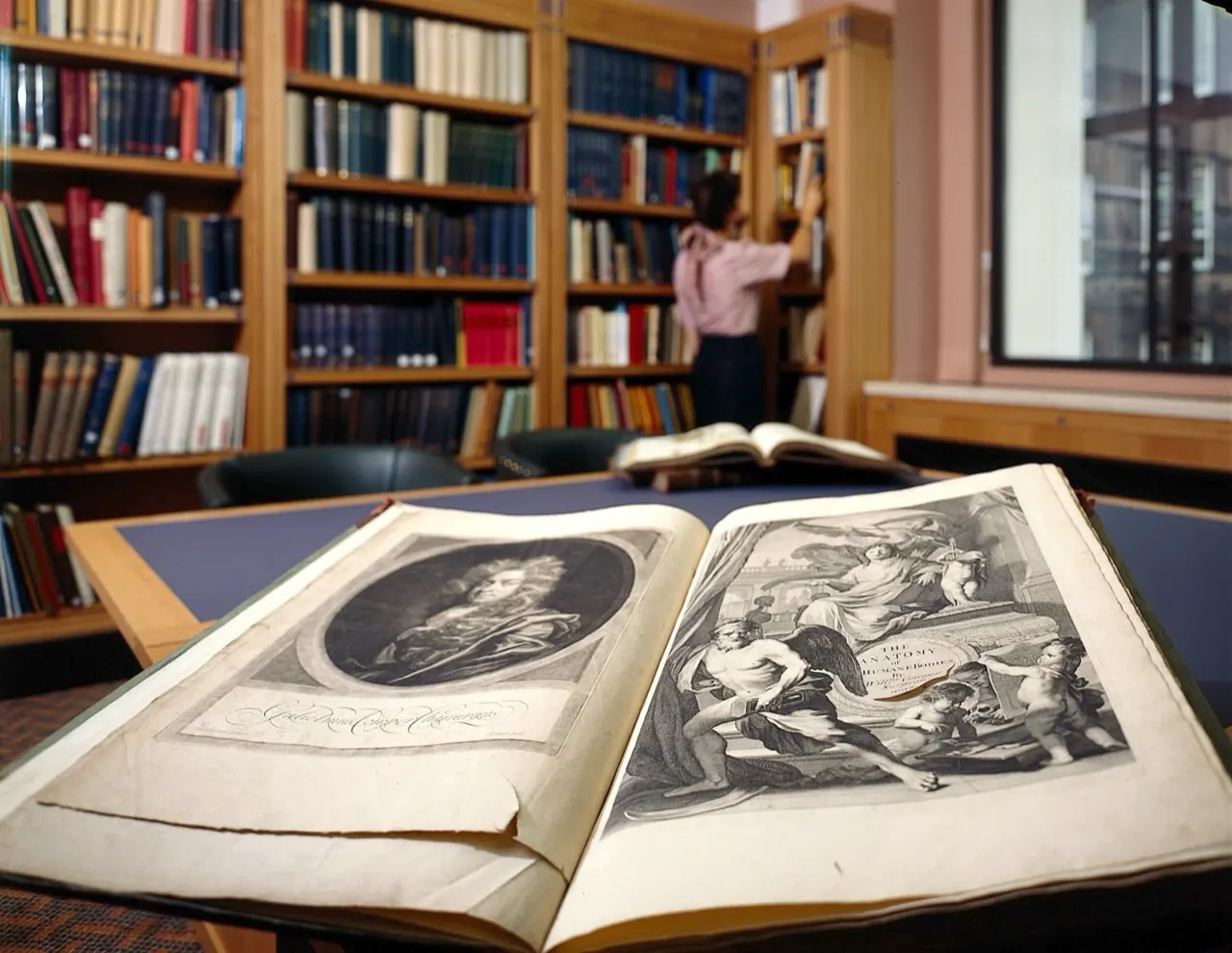 Wellcome Library shelves and an open historical book; contextual documentary image, not the Guinness volume. Wellcome Collection, https://commons.wikimedia.org/wiki/File:Interior_of_Wellcome_library,_shelves_in_Wellcome_L0022582.jpg, CC BY 4.0 (https://creativecommons.org/licenses/by/4.0/). Attribution: Wellcome Collection, “Interior of Wellcome library, shelves in Wellcome L0022582,” CC BY 4.0, via Wikimedia Commons. Resized to 1280 px longest dimension; checked 2026-10-18.