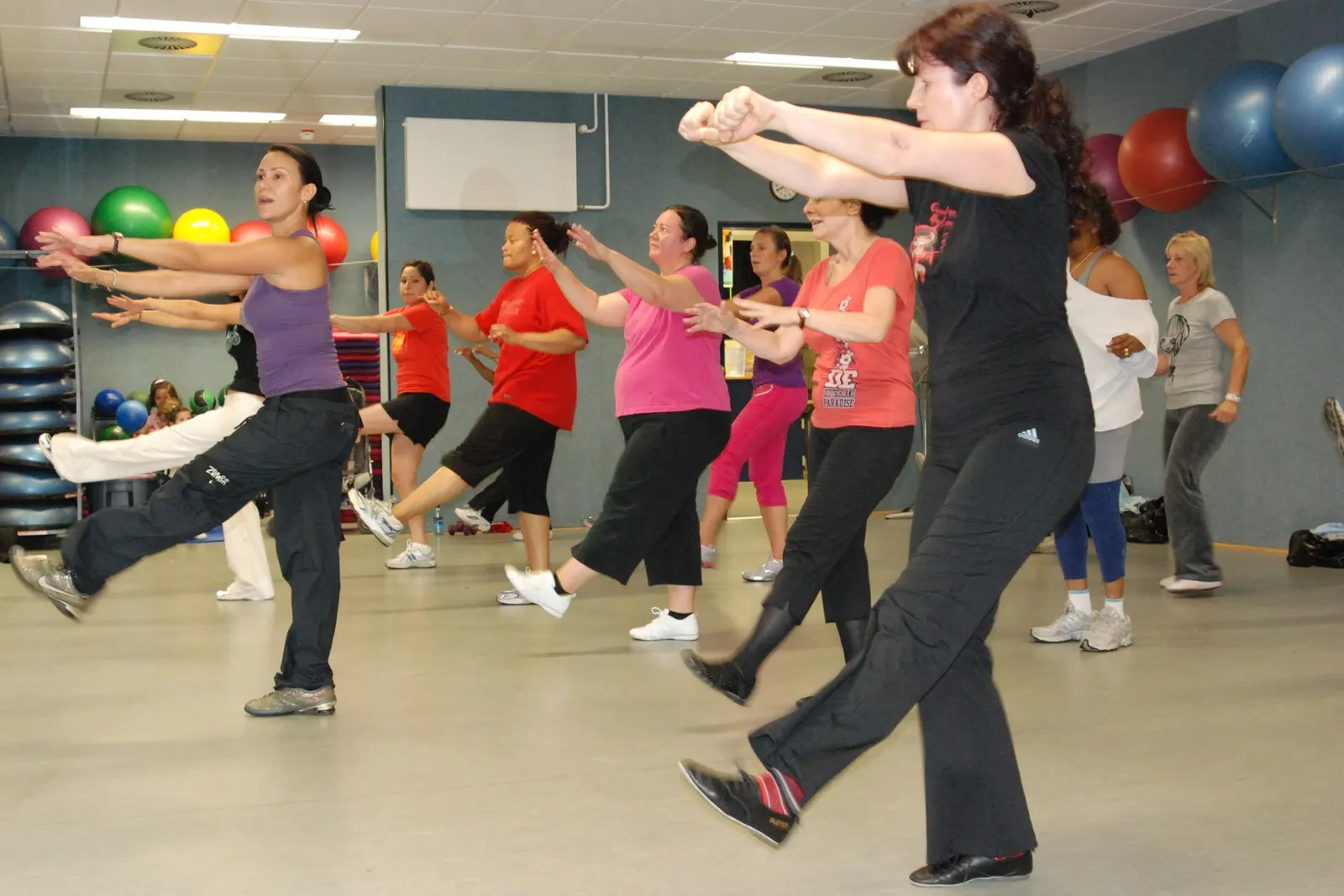 instructor leading a Zumba class at Patch Fitness Center, U.S. Army Garrison Stuttgart, 13 October 2009; photographer Brittany Carlson (USAG Stuttgart); U.S. federal government work, public domain. Source and credit: https://commons.wikimedia.org/wiki/File:US_Army_52862_Zumba_adds_Latin_dance_to_fitness_routine.jpg.