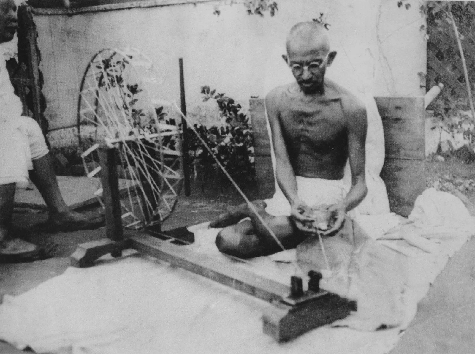 documentary photograph showing Gandhi spinning, described by Commons as late 1940s; original source stated as gandhiserve.org, author unknown. Commons marks it public domain in India and the United States under the listed publication and term rules. Attribution: unknown photographer / gandhiserve.org, via Wikimedia Commons. Source: [File page](https://commons.wikimedia.org/wiki/File:Gandhi_spinning.jpg). Original file, no edits; checked 18 October 2026.