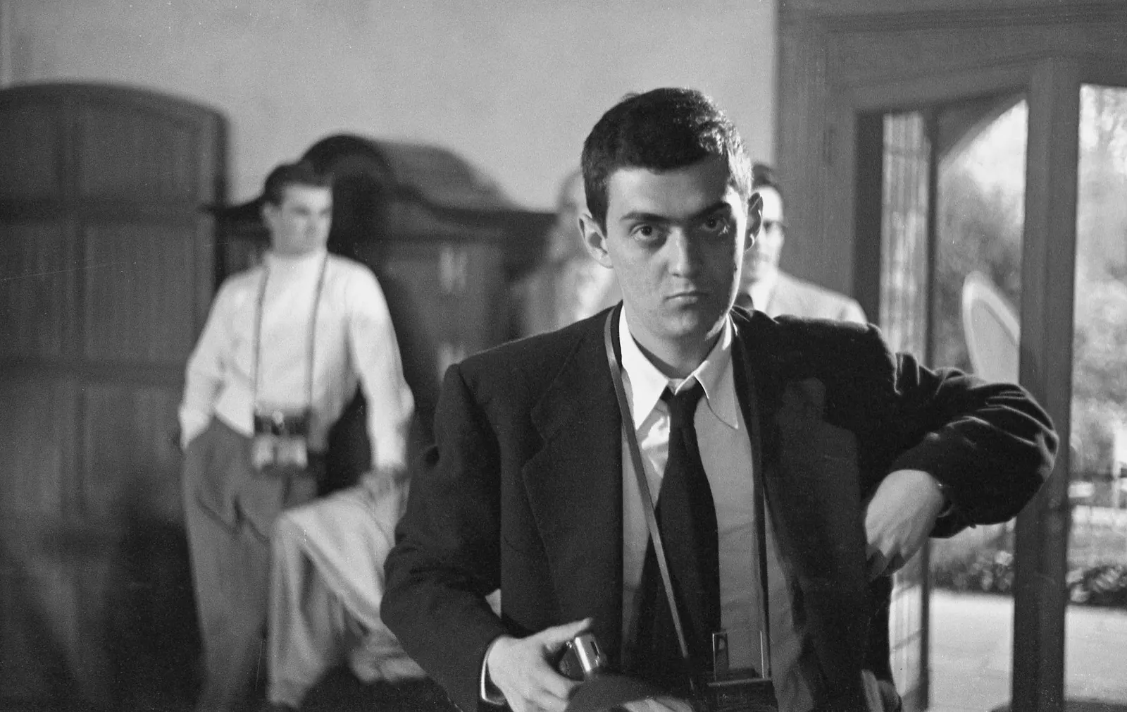 Documentary portrait of filmmaker Stanley Kubrick with a camera at Sadler’s Wells Theatre in 1949. Photographer: Phillip Harrington, for LOOK Magazine. Public domain; Library of Congress LOOK collection states rights were dedicated to the public. Original: https://commons.wikimedia.org/wiki/File:Stanley_Kubrick_(1949_portrait_by_Phillip_Harrington).jpg. Credit retained as Phillip Harrington / LOOK Magazine / Library of Congress. No edits.