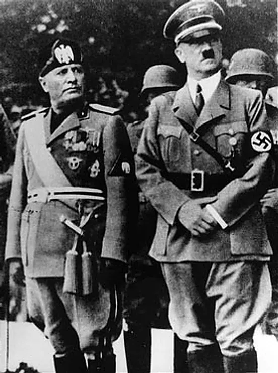archival photograph of Benito Mussolini and Adolf Hitler at a reviewing stand during Mussolini’s official visit to Munich, dated 1937 by the file page. Original asset page: [Wikimedia Commons](https://commons.wikimedia.org/wiki/File:Benito_Mussolini_and_Adolf_Hitler.jpg); source: [United States Holocaust Memorial Museum, photograph 89908](https://www.ushmm.org/uia-cgi/uia_doc/query/1?uf=uia_CLNFQr). Photographer: Muzej Revolucije Narodnosti Jugoslavije. USHMM states that the museum received the donated original and released it to the public domain; Commons marks it public domain. Credit: “Muzej Revolucije Narodnosti Jugoslavije, via USHMM, public domain.” No crop or edits. The image includes Nazi insignia; historical educational use only. Downloaded and visually checked 18 October 2026; 552×740 px.