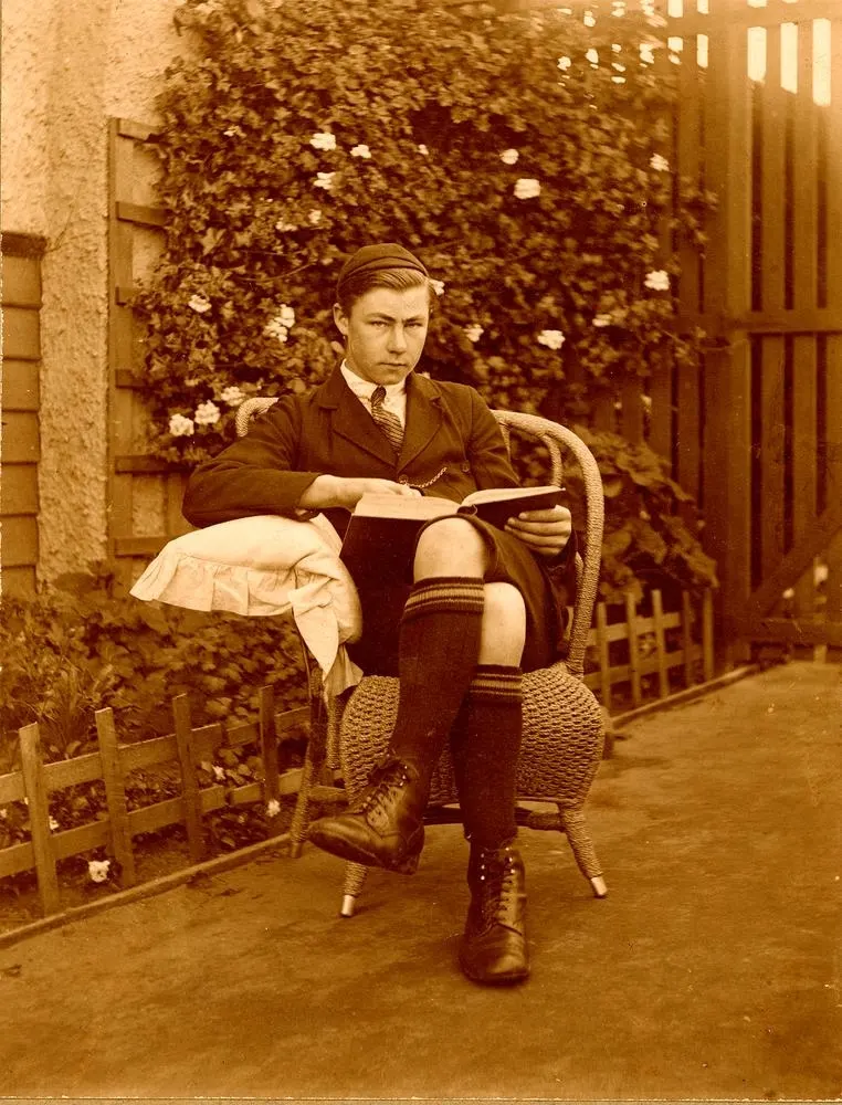 photograph of a 14-year-old boy reading in a garden in Queensland, circa 1910–1920; State Library of Queensland. The library permits reuse with attribution. Source and provenance: https://commons.wikimedia.org/wiki/File:Teenage_boy_reading_a_book_in_the_garden,_1910-1920_(6752288625).jpg.
