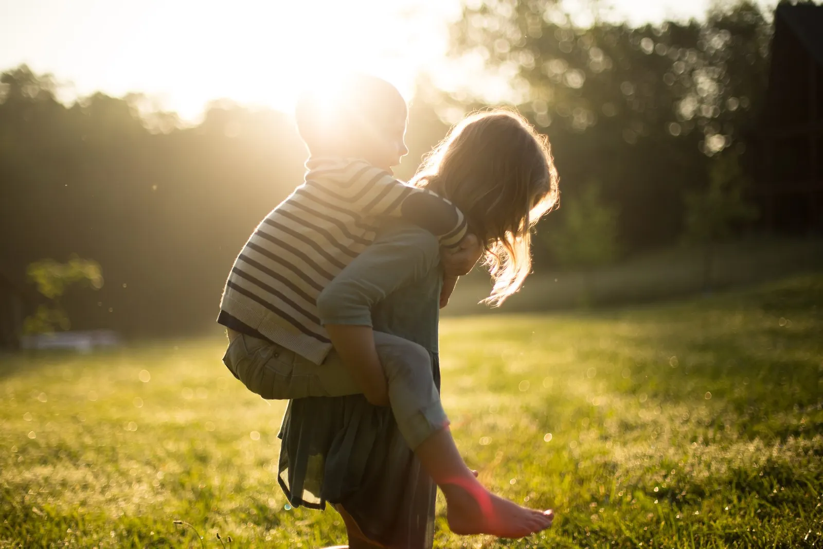 documentary photograph of a parent carrying a child piggyback, by Jenn Evelyn-Ann (jenn_azraimages); CC0 1.0. Original: https://commons.wikimedia.org/wiki/File:Piggy-back_ride_(Unsplash).jpg. Attribution retained for provenance. Resized to fit 1800 px and saved as optimized JPEG quality 88.