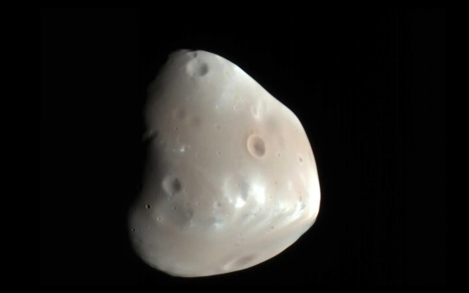 Color-enhanced NASA image of Deimos taken by HiRISE aboard Mars Reconnaissance Orbiter on 21 February 2009. Credit: NASA/JPL-Caltech/University of Arizona. Original: https://www.nasa.gov/image-article/mars-moon-deimos/; direct asset: https://science.nasa.gov/wp-content/uploads/2017/11/deimos-1920x1200-1.jpg.