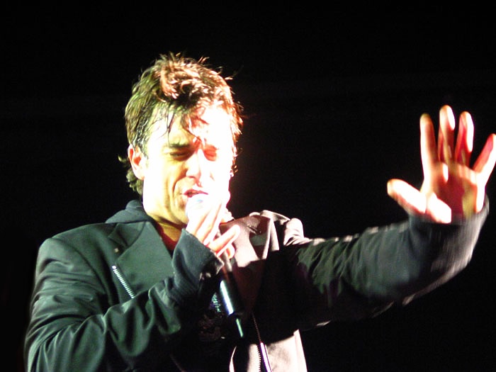 Robbie Williams performing in Sydney. Photographer Amanda, Robbie Williams Gallery/Lypton Village; https://commons.wikimedia.org/wiki/File:Robbie_Williams_singing_in_concert.jpg; CC BY 2.5. Attribution: “Robbie Williams singing in concert” by Amanda, CC BY 2.5, via Wikimedia Commons. No edits.