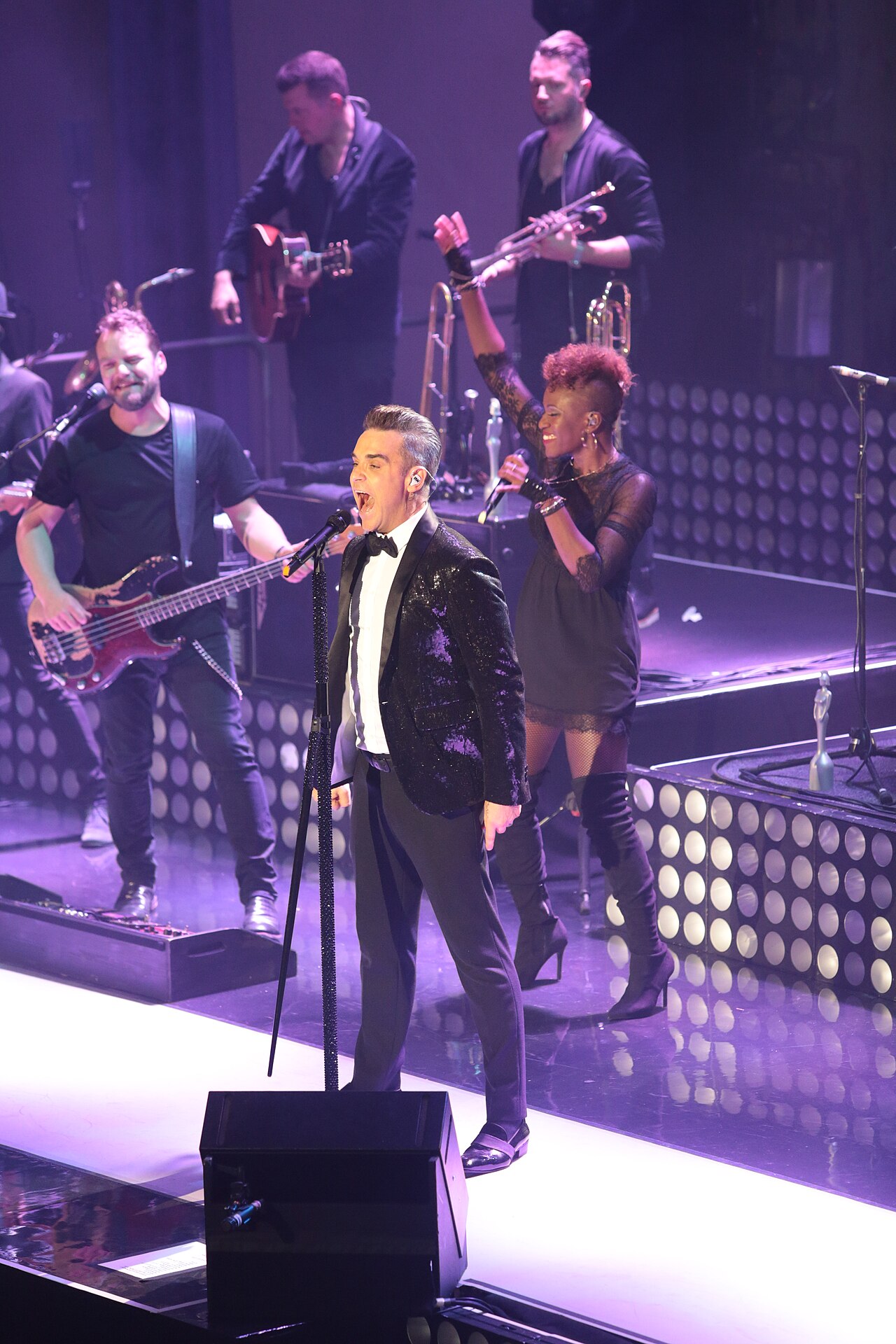 Robbie Williams performing at Troxy, Nov. 7, 2016. Photographer Jbanham91; https://commons.wikimedia.org/wiki/File:Robbie_Williams_performing_at_Troxy.jpg; CC BY-SA 4.0 (as stated on Commons). Attribution: “Robbie Williams performing at Troxy” by Jbanham91, CC BY-SA 4.0, via Wikimedia Commons. Served at reduced width (1280 px); no crop.
