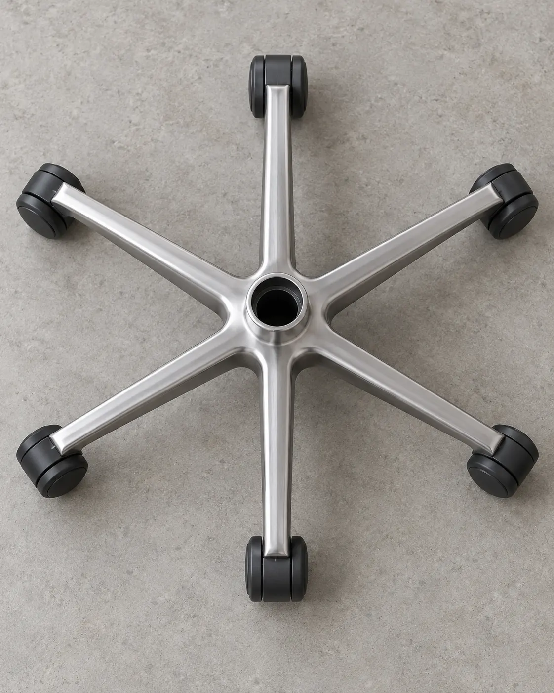 AI-generated top-down illustration of a generic six-arm office chair base with casters; not the actual record chair. Prompt: “Photorealistic vertical 4:5 top-down editorial detail of a custom swivel office-chair base, isolated on a neutral floor. The star-shaped base has exactly six evenly spaced arms and one caster wheel at the end of each arm, all six casters clearly visible. Generic unbranded component, illustrative only, not the actual record chair. No seat, no text, no labels.” Generated 20 October 2026.