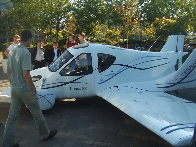 side view of Terrafugia’s Transition flying prototype with wings extended, photographed by Matt Brown (Flickr user Londonmatt). Commons caption identifies a SciFoo 2008 display, but embedded camera metadata gives 20 August 2005; the exact date/event is uncertain, so the image is used only to show the aircraft, not as date evidence. CC BY 2.0; credit “Matt Brown / Londonmatt,” no changes. Original page: https://commons.wikimedia.org/wiki/File:Terrafugia_Transition_at_SciFoo2008_GoogleHQ.jpg.