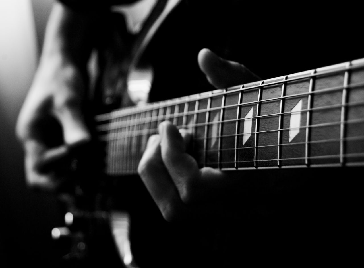 Close-up of an electric guitarist’s instrument; Feliciano Guimarães, CC BY 2.0. Wikimedia Commons page: https://commons.wikimedia.org/wiki/File:Electric_guitar_(477100921).jpg. Attribution: Feliciano Guimarães; no edits.