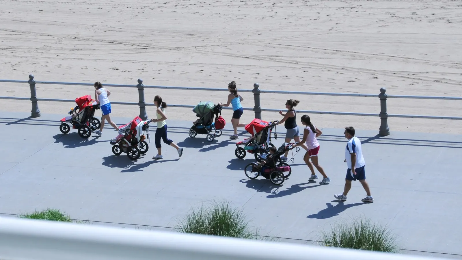group of women running with strollers; photographer Serge Melki; CC BY 2.0. Original: https://commons.wikimedia.org/wiki/File:Attack_of_the_stroller_Moms_(4665101120).jpg. Attribution: Serge Melki, CC BY 2.0, via Wikimedia Commons. Visually inspected 2026-10-18.